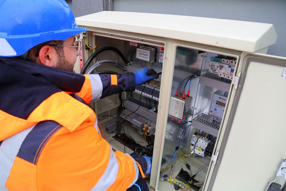 Électricien en casque devant un grand tableau électrique ouvert